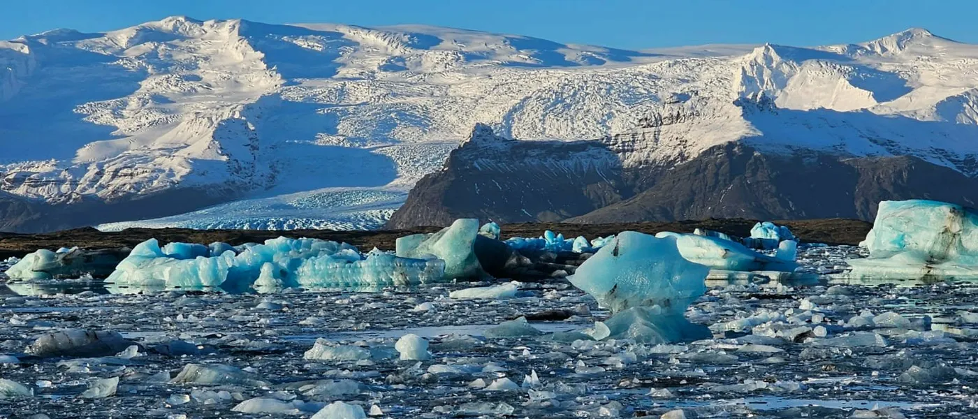 Blue icebergs on Jökulsárlón, with the glacier tongue and snow-covered mountains behind
