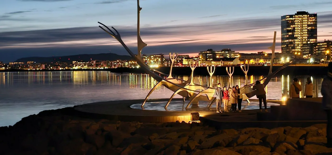 The Sun Voyager sculpture from the east, with lit tower blocks behind it